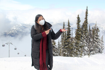 Latin adult woman arrives in Canada and discovers the snowy mountains with a face mask due to the...