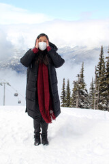 Latin adult woman arrives in Canada and discovers the snowy mountains with a face mask due to the...