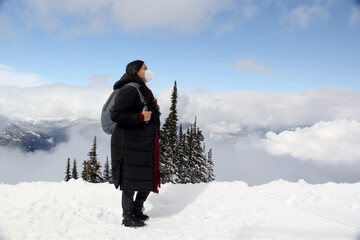 Latin adult woman arrives in Canada and discovers the snowy mountains with a face mask due to the...