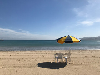 Empty sandy beach with colored umbrella and chairs