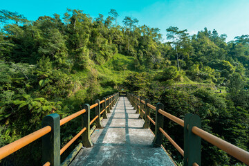 Obraz premium Iconic bridge in one of the tourist destinations in Kali Kuning, Sleman, Indonesia with green hills in the morning