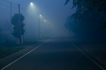 road in the city on a dark evening with heavy fog, illuminated by LED street lights