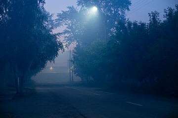 road in the city on a dark evening with heavy fog, illuminated by LED street lights