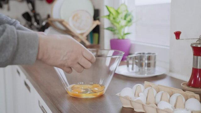 man breaking egg big glass bowl with eggs cooking omelet on the breakfast kitchen interior