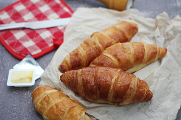 A pile of delicious fresh croissants served with butter on a gray table.