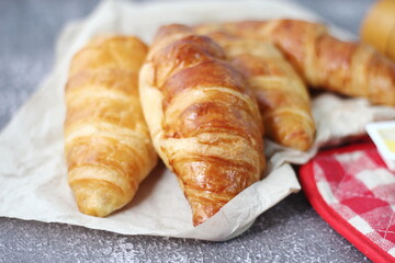 A pile of delicious fresh croissants served with butter on a gray table.