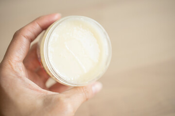 a jar of cream for the face, body, in the hands of a woman, on a light background. cosmetics, natural care, organic cream, moisturizing, care, beauty, cosmetics production, cream