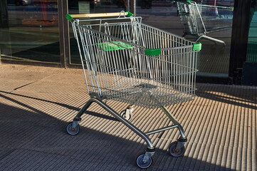 Cart for grocery products standing near the entrance to the supermarket on the street