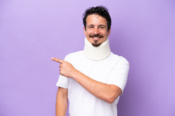 Young caucasian man wearing neck brace isolated on purple background pointing to the side to...