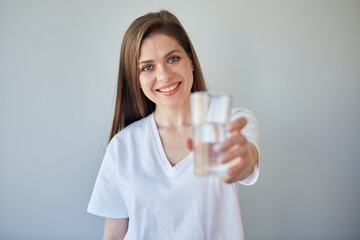 Smiling woman holding water glass. isolated portrait of girl wearing white shirt.