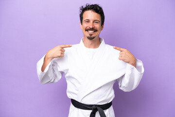 Young caucasian man doing karate isolated on purple background giving a thumbs up gesture