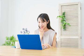 リビングでノートパソコンを見て驚く女性