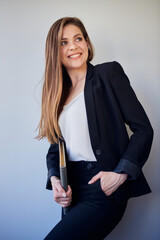 Woman teacher in black business suit and white shirt keeps hand in pants pocket looking away. isolated profile portrait.