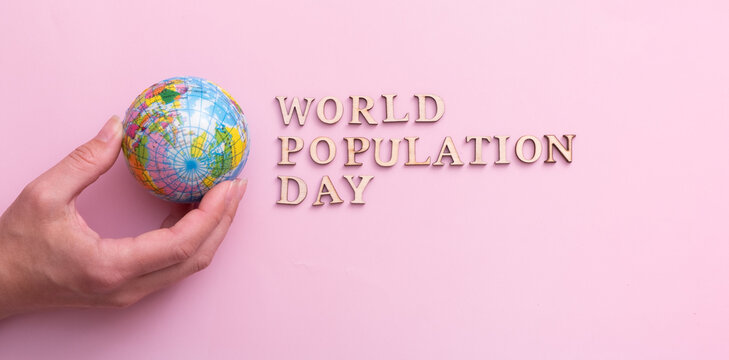 World population day write by wooden letter with globe in woman hand