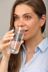 Woman drink water from glass. Close up face portrait, girl looks away.