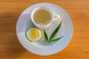 Cup of Marijuana herb and lemon hot tea on the plate.