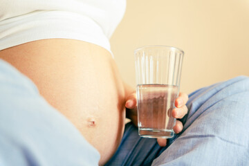 Drinking water pregnant woman. Young pregnancy mother drink water. Pregnant lady waiting of baby. Glass of water. Concept maternity, childbirth.