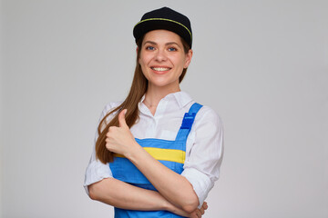 Smiling Woman in blue overalls and black cap doing thumb up. Happy girl worker isolated portrait.