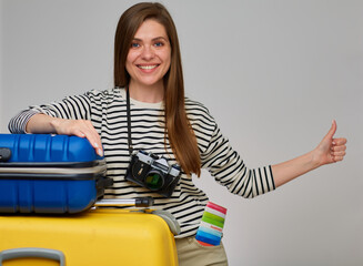 Hitchhiking travel for smiling woman with travel bags and photo camera. Girl holding thumb up.