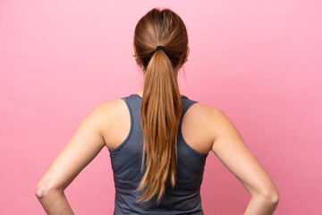 Young sport caucasian woman isolated on pink background in back position