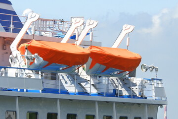 The lifeboats on the ship are covered with orange covers.