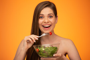 Happy woman eating salad, girl with bared shoulders and long hair isolated portrait on orange yellow background.