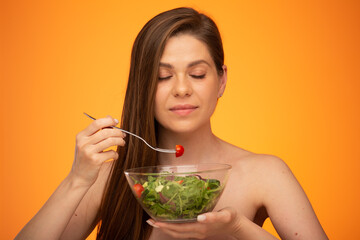 Happy dreaming woman eating salad with closed eyes, girl with bared shoulders and long hair isolated portrait on orange yellow background.