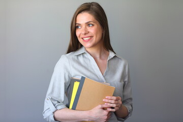 Smiling young woman teacher with work books looking away.