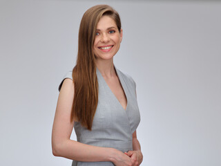 Smiling woman in gray business dress standing with folded hands, isolated on gray background.