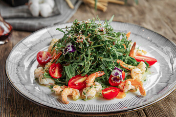 Portion of gourmet shrimp and arugula salad on wooden background