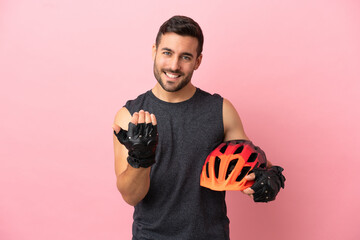 Young cyclist man isolated on pink background inviting to come with hand. Happy that you came - obrazy, fototapety, plakaty