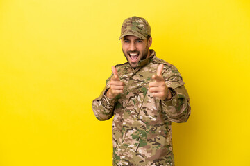 Military man isolated on yellow background pointing to the front and smiling