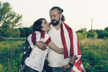 Loving couple celebrating USA Independence Day. Couple in love kissing and holding USA flag