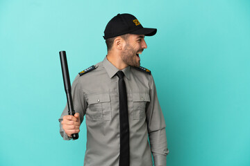 Young security man isolated on blue background laughing in lateral position