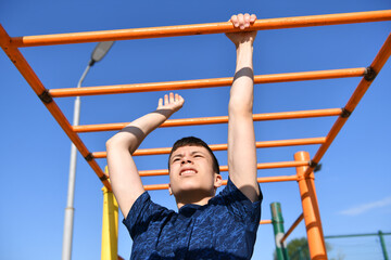 a teenage boy trains on a sports ground outdoors, he does physical exercises, a healthy lifestyle, a bright sunny day in summer