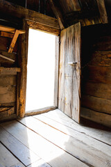 Obraz premium Opened door of an old wooden cottage with white blank space for your photo