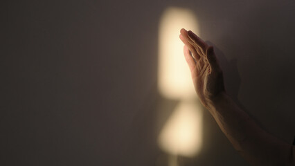 man hand playing with sun light against white wall