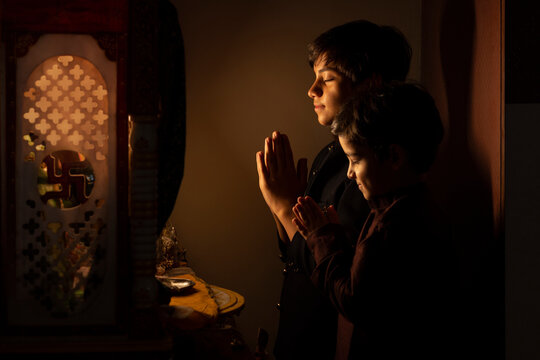 Portrait of two brothers praying together to God with folded hands