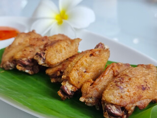 Fried chicken wings on a plate with rests and a cup of dipping sauce