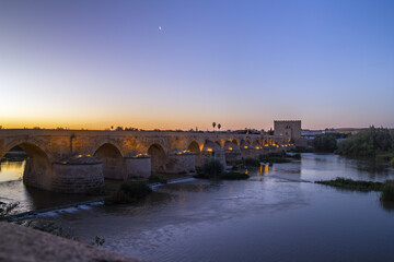 Fototapeta na wymiar Ancient roman bridge across the Guadalquivir river in the morning twilight in the medieval city of Cordoba, Andalusia. Spain