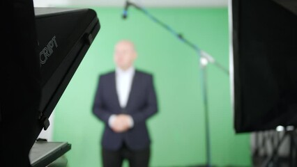 Television presenter talking to camera using a teleprompter in a green screen studio