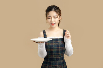 Happy beautiful Asian model holding a plate with copy space for separate products on beige...