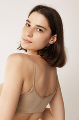 Close-up portrait of young beautiful woman with short brown hair posing isolated over grey studio background