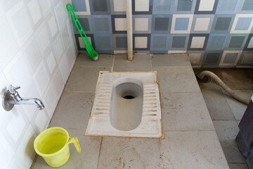 An Asian squat style toilet and bathroom in an unhygienic condition. India