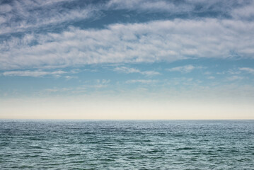The surface of the sea under a cloudy blue sky. Blue wave surface of the sea going to the horizon.