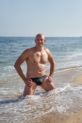 Fototapeta na wymiar bald man on the beach by the sea on vacation