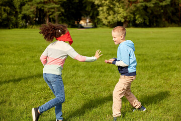 childhood, leisure and people concept - group of happy children playing tag game and running at park