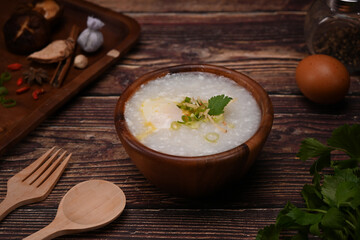 Testy rice porridge with soft boiled egg, and spring onion in wooden bowl for healthy breakfast