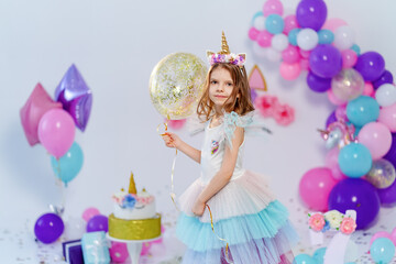 Obraz na płótnie Canvas Unicorn Girl holding gold confetti air baloon. Idea for decorating unicorn style birthday party. Unicorn decoration for festival party girl