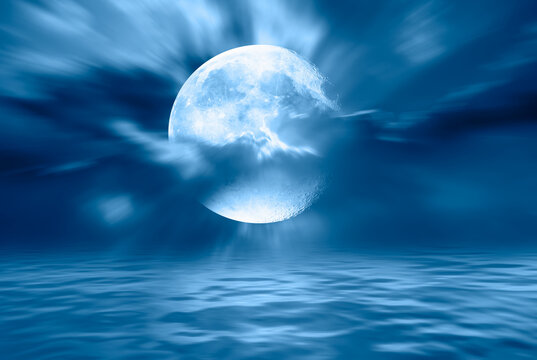 Night sky with blue moon in the clouds over the calm blue sea "Elements of this image furnished by NASA